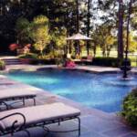 "Classic wrought iron chaise lounges and a brick fireplace, along with plantings from Horticare, ring the pool."