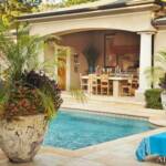 "A tropical paradise awaits... featuring landscaping by designer Chris Olsen, a pool  by Brooks Pool Co. and stonework by Joe Murdaugh Masonry. On stone ledges at the four corners of the pool, Olsen added containers from Botanica Gardens filled with Phoenix roebelenii palms and colorful annuals."