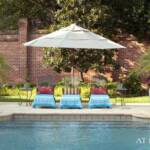 "Bright turquoise towels contrast with the surrounding landscaping…Woodard iron chaises and mosaic iron side tables are from Ken Rash’s Arkansas; containers are from Botanica Garden. The pool, designed by Brooks Pool Co., features tile edging and bench seating."